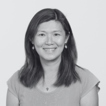 Smiling person with shoulder-length hair against a plain white background.